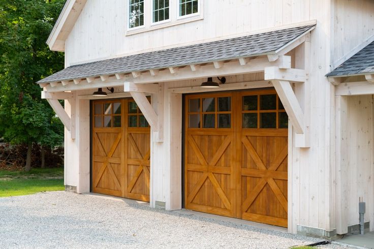 two wooden garage doors in front of a white house