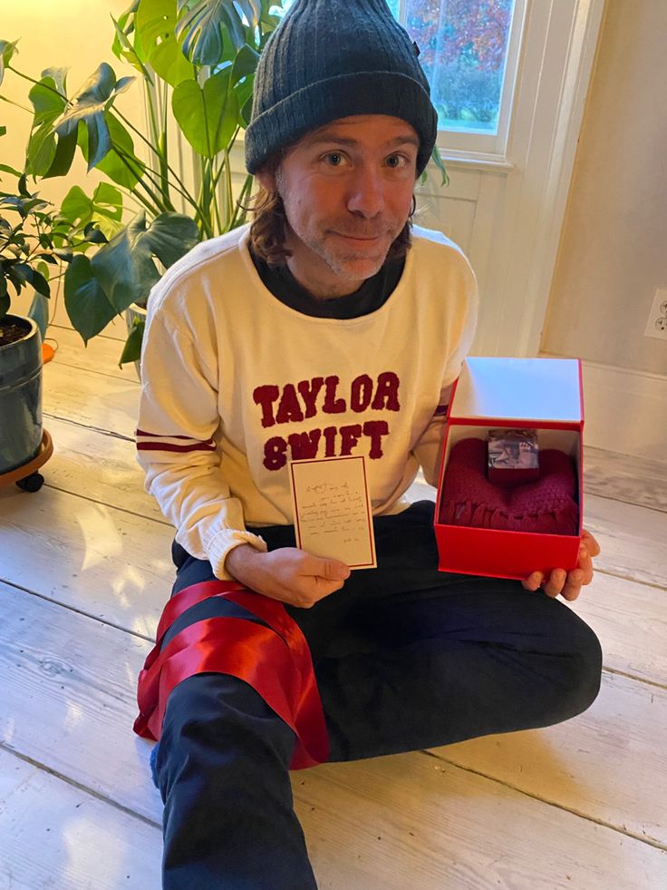 a man sitting on the floor holding up a box with an award in front of him