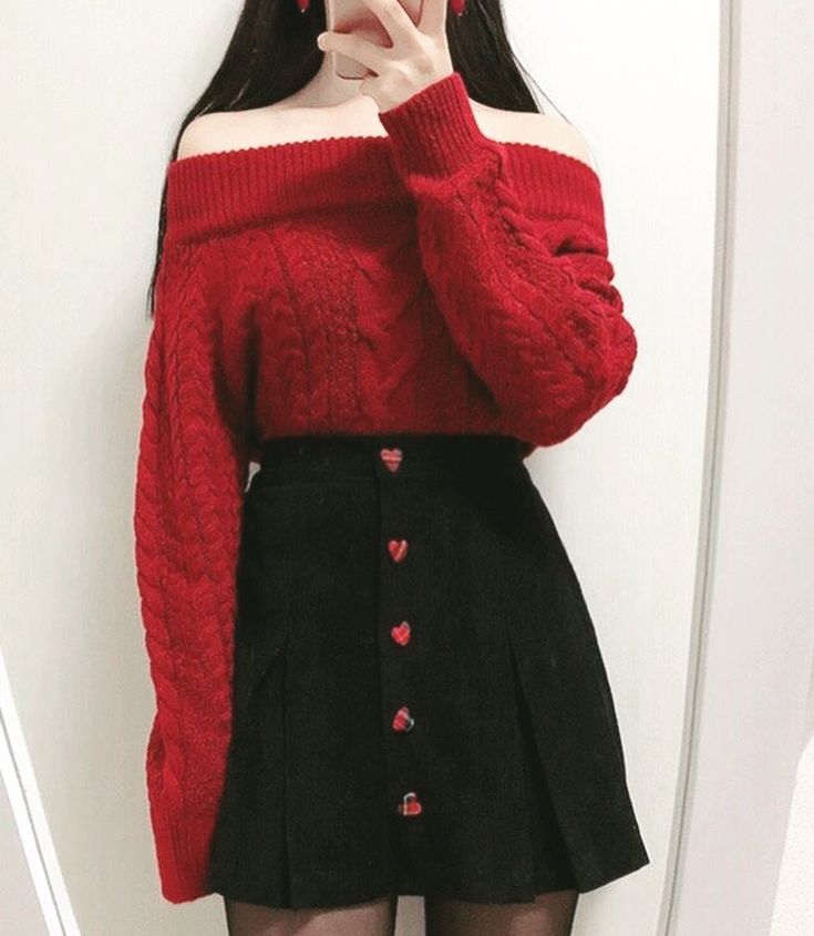 a woman taking a selfie in front of a mirror wearing a red sweater and black skirt