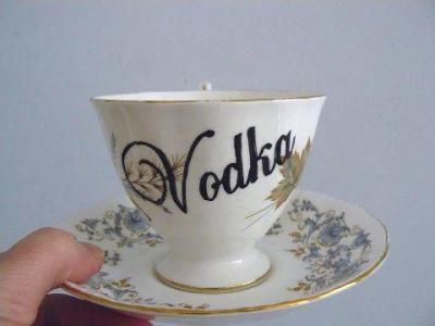 a hand holding a cup with the word vodka written on it and gold trimmings