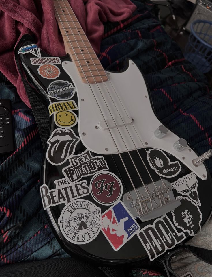 an electric guitar with many stickers on it's body and neck, sitting on a blanket