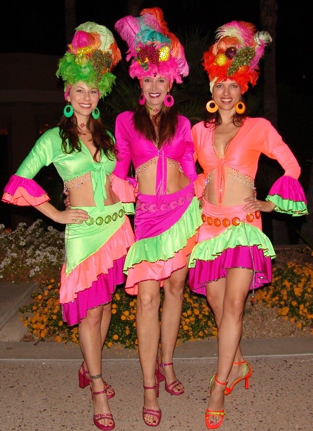 three women in brightly colored costumes posing for the camera with their hands on their hipss