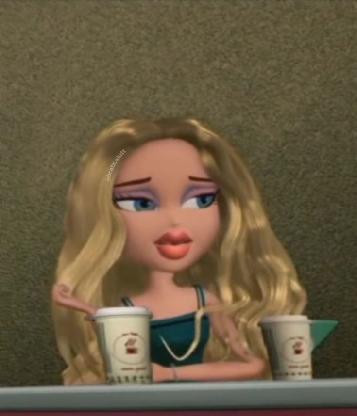 a doll with blonde hair sitting at a table holding two coffee cups