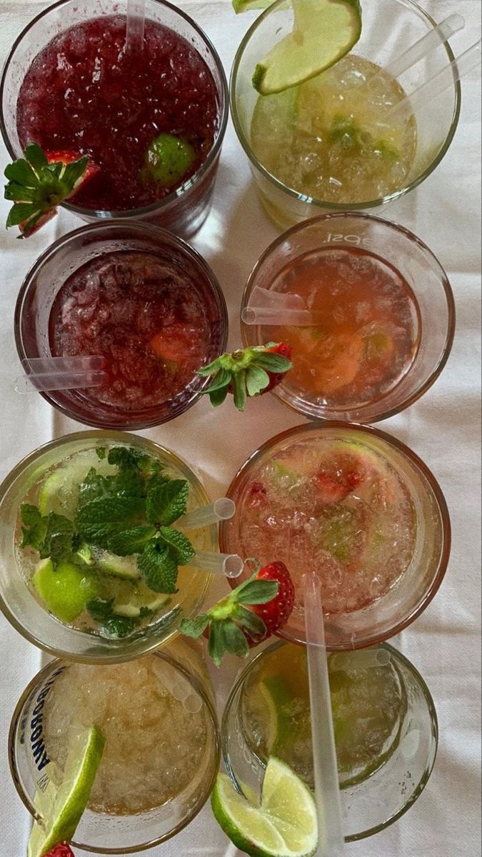 several glasses filled with different types of drinks and garnishes on a table