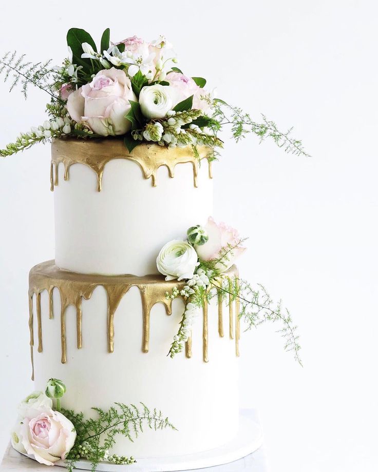 a three tiered cake with flowers and dripping icing