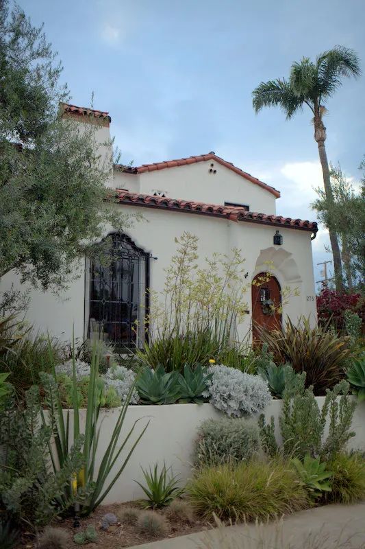 a house with plants and trees in front of it