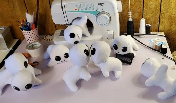 several white stuffed animals sitting next to a sewing machine