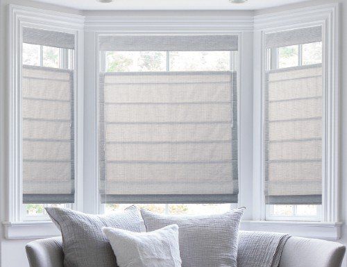 a living room filled with furniture and two windows covered in roman blind shades on the windowsill