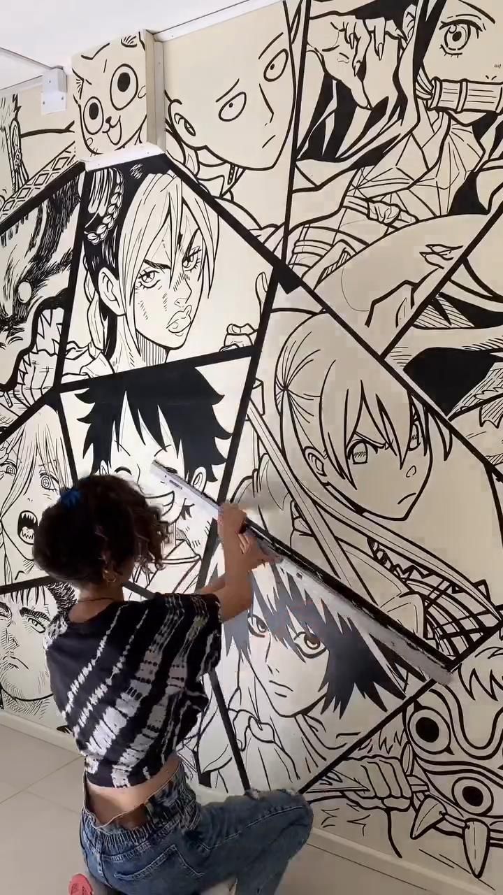 a woman is painting a wall with anime characters on it