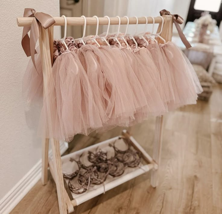 a rack with some pink tulle skirts hanging from it's hooks on a wall