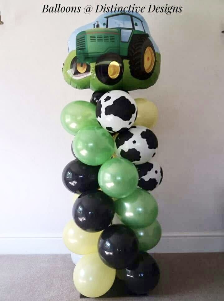 a green tractor with black and white balloons in the shape of a stack of farm animals