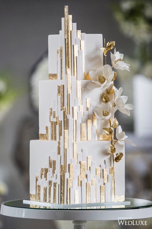 a white and gold wedding cake with flowers on top