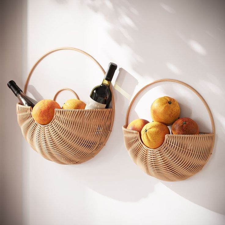 two wicker baskets with wine bottles and oranges in them hanging on the wall