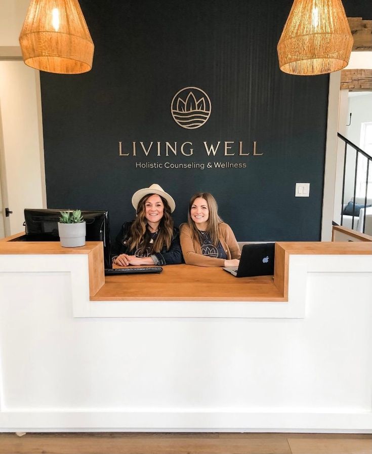 two women sitting at the front desk of living well