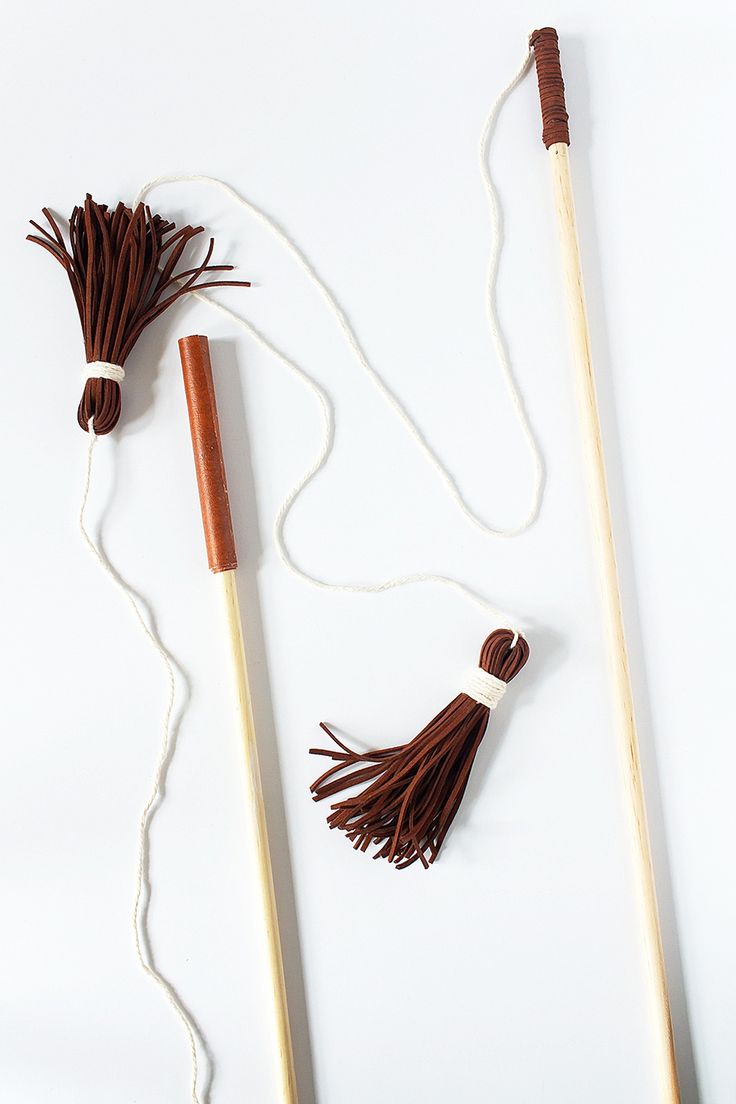 two wooden sticks with tassels attached to them sitting on a white surface next to a string