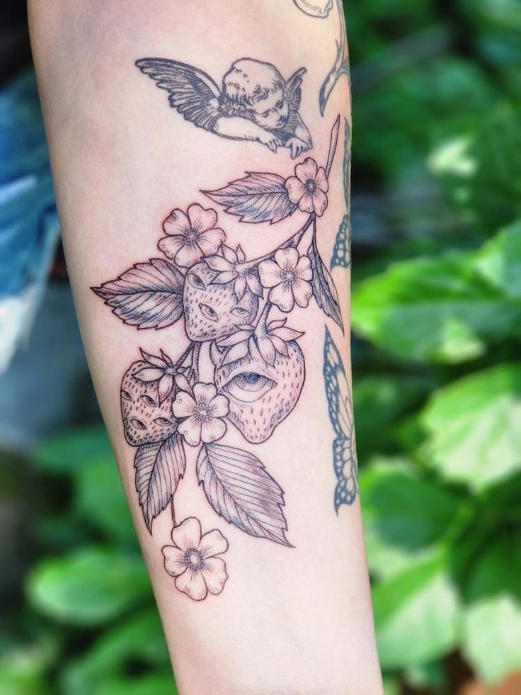 a woman's arm with flowers and a bird on the branch in front of her