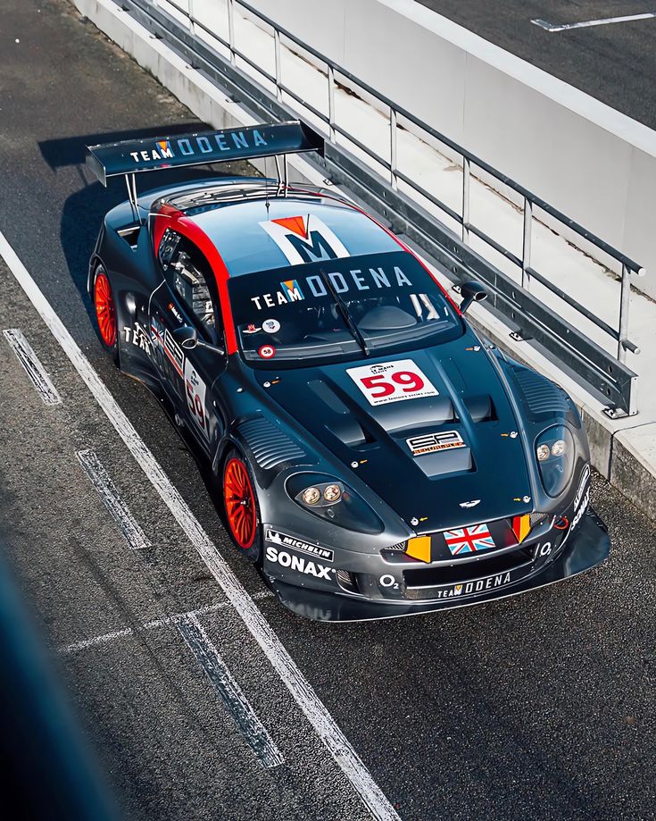 a race car driving down the road in front of a barrier on top of a hill