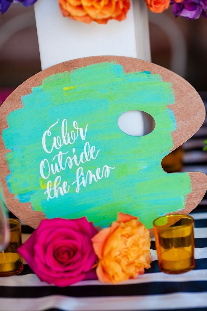 a wooden sign that says color outside the line with flowers around it on a table