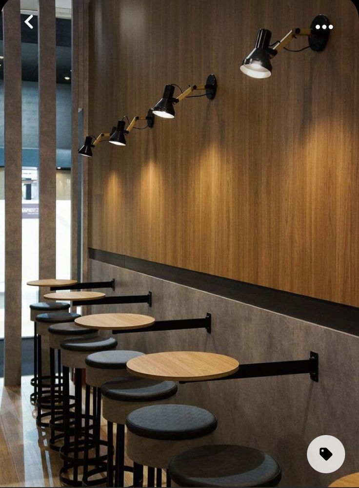 a row of stools in front of a wooden wall with lights on the side