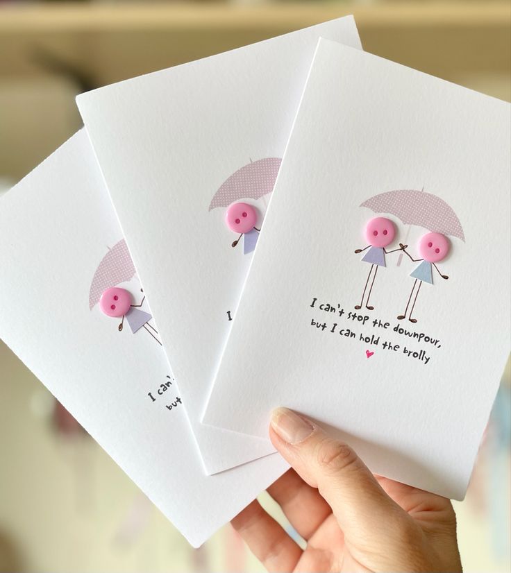 three cards with pink buttons are held up