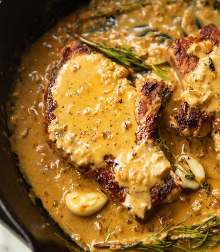 some meat and gravy in a bowl with asparagus