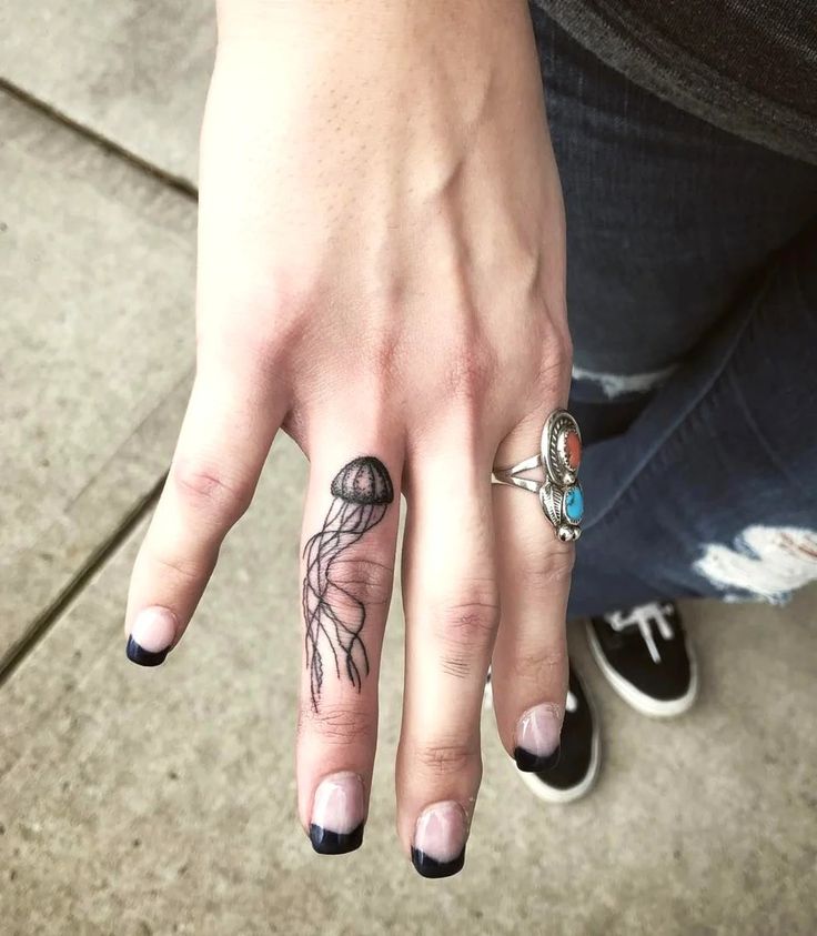 a woman's hand with tattoos and rings on it