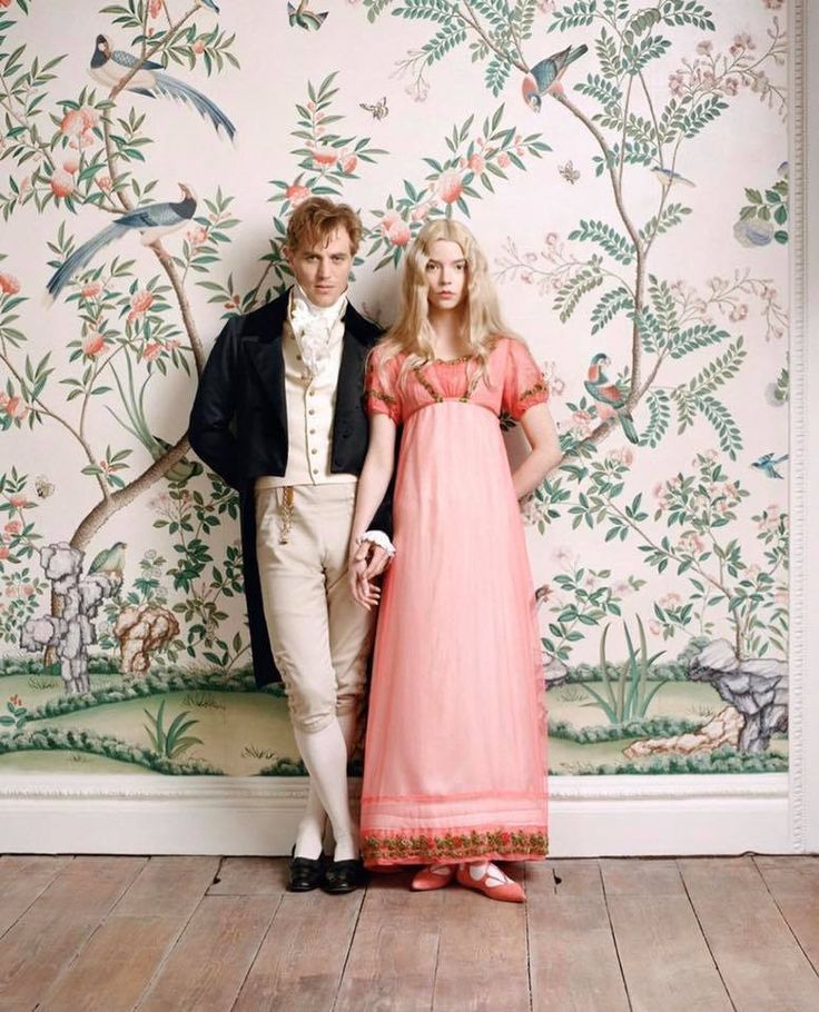 a man and woman standing next to each other in front of a wall with birds on it