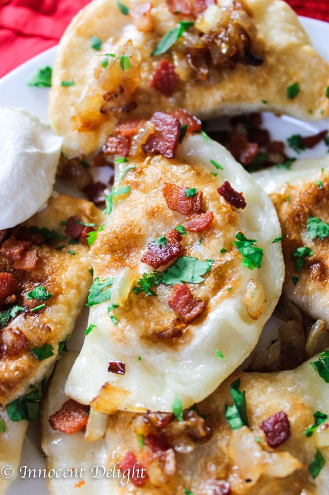 a white plate topped with dumplings covered in cheese and bacon