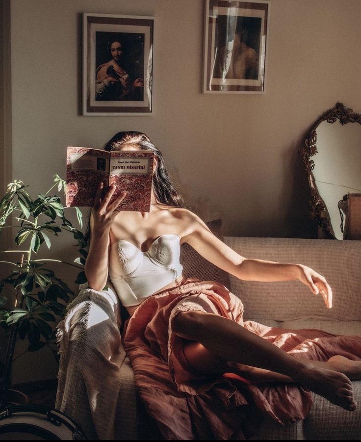 a woman sitting on a couch reading a book