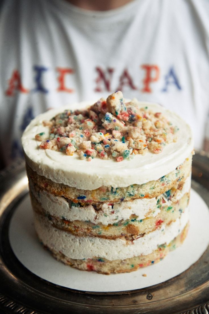 a cake with white frosting and sprinkles on it sitting on a plate