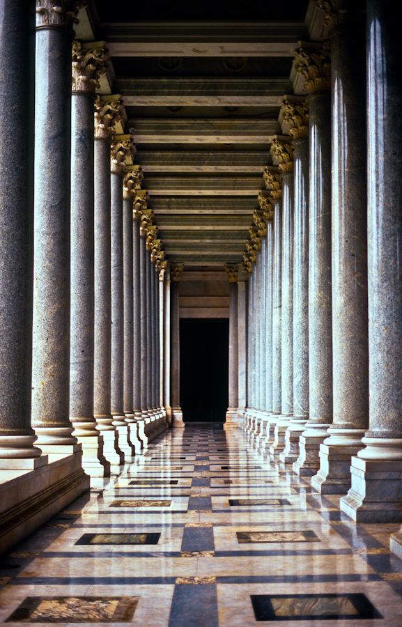 an empty hallway with columns and marble flooring