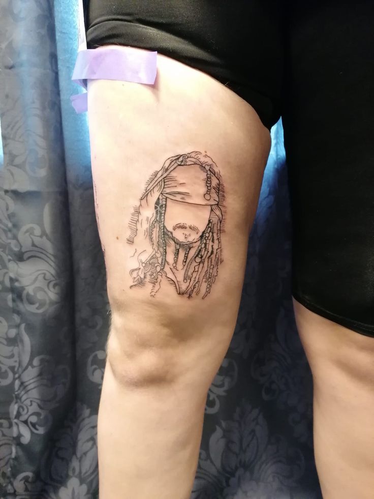 a woman's thigh with a tattoo of a man wearing a bandana on it