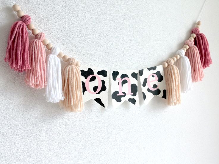 a cow print banner with tassels hanging on the wall next to a white wall