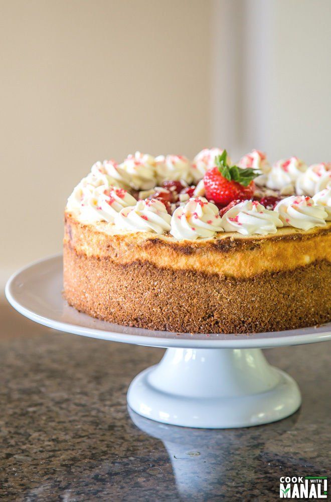 a cake with whipped cream and strawberries on top is sitting on a white pedestal