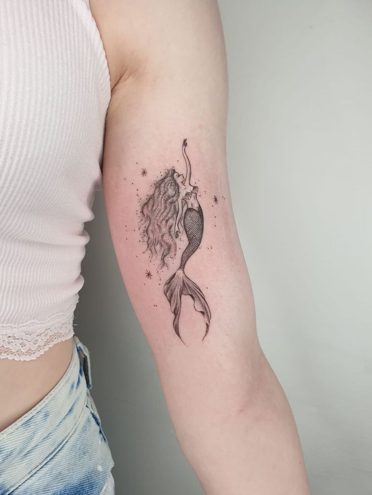 a woman's arm with a mermaid tattoo on the left side of her body