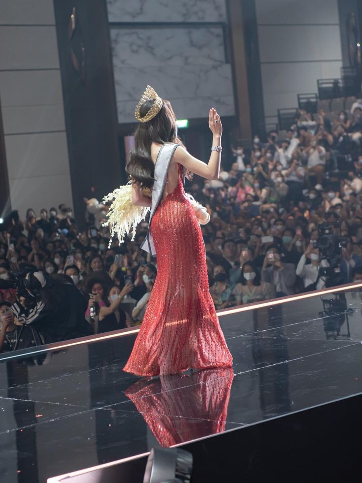 a woman in a red dress walking down a runway