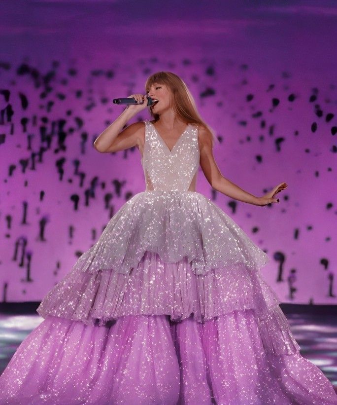 the singer is performing on stage wearing a purple dress