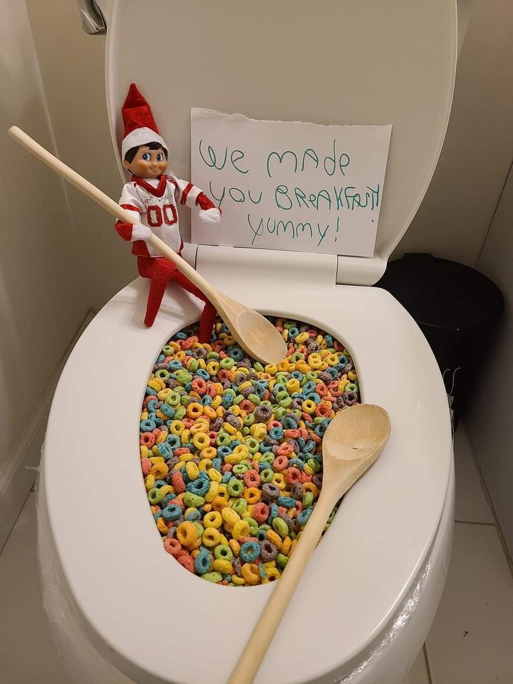 an elf is sitting on the toilet with cereal in it and a sign that says, don't feed me