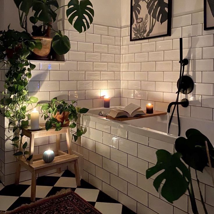 a bathtub with candles and plants in it next to a black and white checkered floor