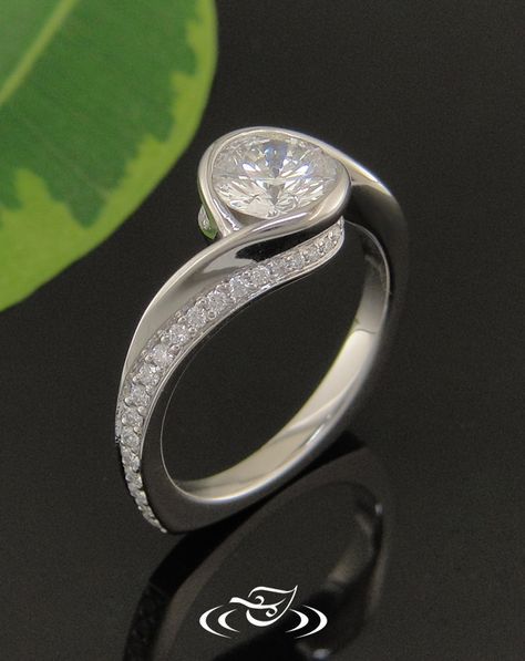 a diamond ring on a black surface with a green leaf in the background and an advertisement for