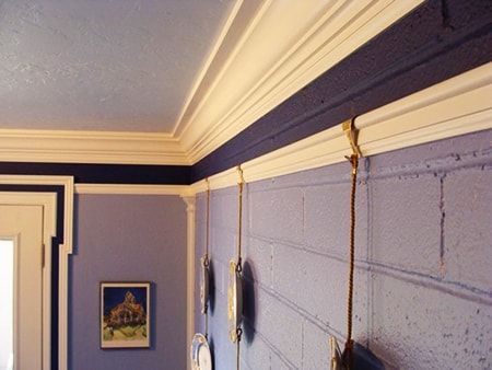 a bedroom with blue walls and white trim on the ceiling, along with two hanging telephones