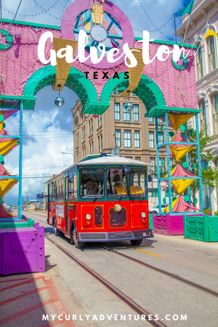 a red trolley car driving down a street next to a colorful sign that says charleston texas