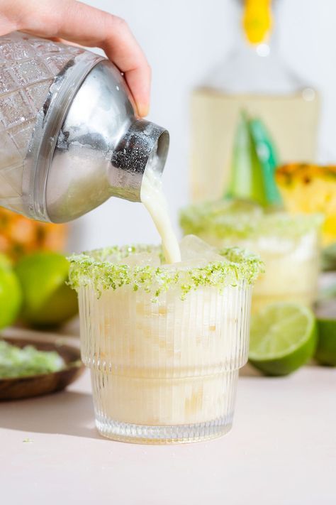 someone is pouring something into a cup with limes and other ingredients in the background