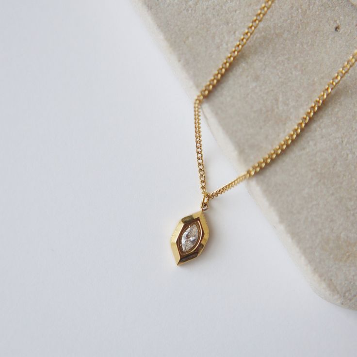 Introducing our Marlow Necklace, a testament to timeless elegance and refined minimalism. The marquise shape gracefully frames a CZ stone, adding a touch of sparkle and radiance. Its minimalistic style makes it perfect for any occasion. -stainless steel, gold plated -15.5" with 2" extender Modern Gold Jewelry With Diamond Eyes, Gold Necklace With Single Marquise Cut Diamond, Gold Necklace With Marquise Cut Diamond, Gold Marquise Cut Necklace With Single Diamond, Gold Marquise Cut Necklace For Gift, Dainty Marquise Cut Gold Jewelry, Dainty Gold Marquise Cut Jewelry, Timeless Gold Necklace With Marquise Shape, Timeless Gold Marquise Necklace