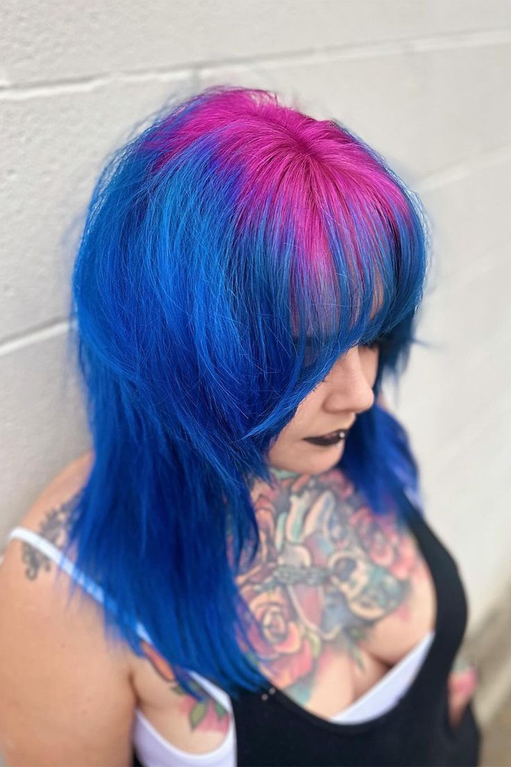 Witness the striking combination of bright pink roots and blue hair with bangs on the right side of this person's head! 💖💙 Embrace your adventurous side and make a statement with this eye-catching hairstyle. Ready to stand out from the crowd? Book your appointment now and let's create your own unique look! #BrightPinkRoots #BlueBangs #ColorfulHair #HairInspiration #BookNow #HairMagic Roots Different Color Hair, Unique Vivid Hair Color, Blue Hair Pink Bangs, Hair Dye Ideas Bright, Blue Hair With Pink Tips, Pink And Blue Hair Dye Ideas, Blue Hair Pink Tips, Hair Color Ideas Crazy, Purple Roots Blue Hair