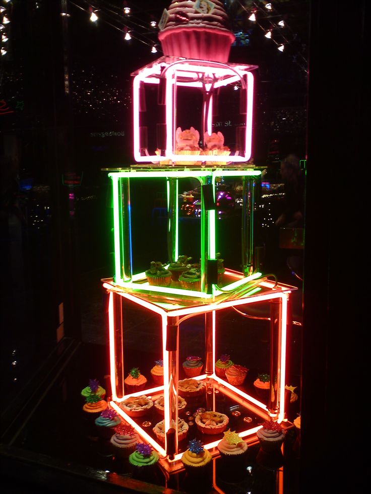 three tiered display with cupcakes in the middle and lit up lights above