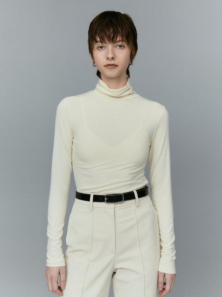 This is a turtleneck top with full-length sleeves, designed for a sleek and fitted look. The neckline is high and folds over, typical of a turtleneck style, which can provide warmth and a sophisticated appearance. The fabric appears smooth and possibly has some stretch, which would allow a close fit to the body.- The turtleneck's structure is ideal for cooler weather and can be used as a layering piece under jackets or sweaters.- Its overall design is minimalist, with no visible patterns or embellishments, offering a clean and versatile look.- The tailored fit and simple elegance make it a suitable choice for both casual and more formal settings. Elegant Long Sleeve Mock Neck Top For Winter, Solid Fitted High Neck Turtleneck, Sleek Long Sleeve Turtleneck For Layering, Sleek Turtleneck With Funnel Neck, Elegant Mock Neck Turtleneck Top For Winter, Elegant Spring Turtleneck For Layering, Sleek Long Sleeve Turtleneck For Fall, Sleek Fitted Solid Turtleneck, Sleek Fitted Turtleneck