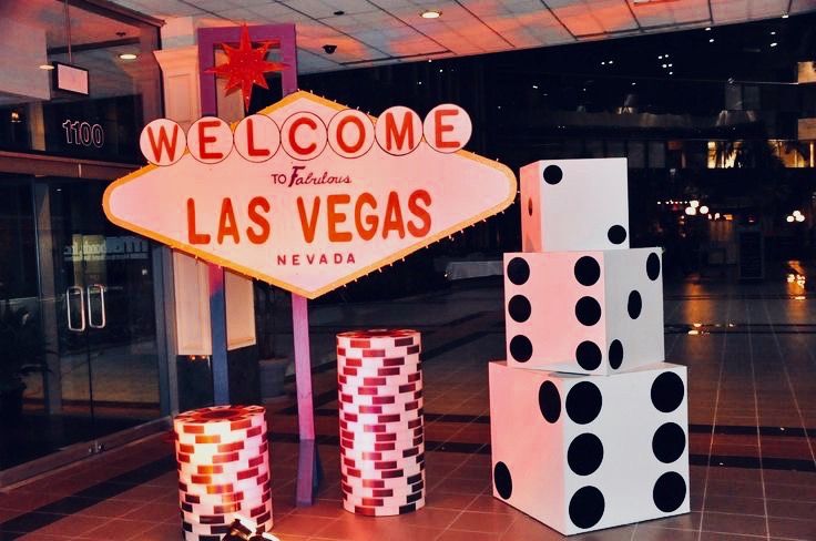 the las vegas sign is lit up in pink and black polka dots, with dices stacked next to it