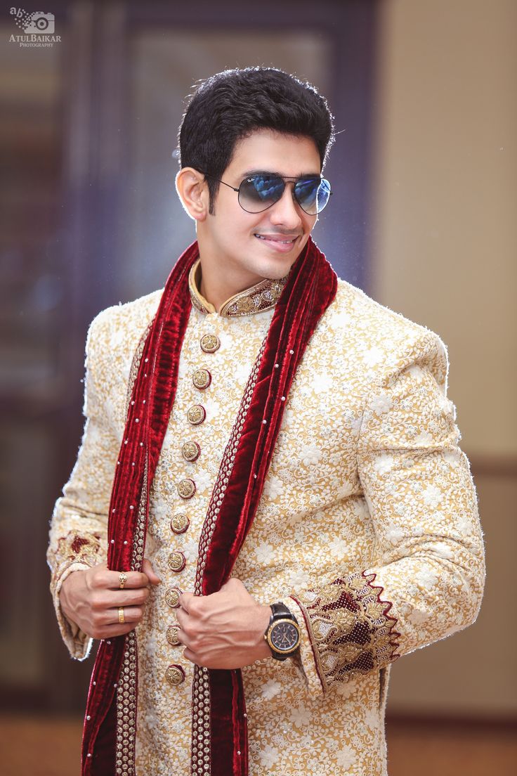 a man in a white suit and red scarf posing for the camera with his hand on his hip