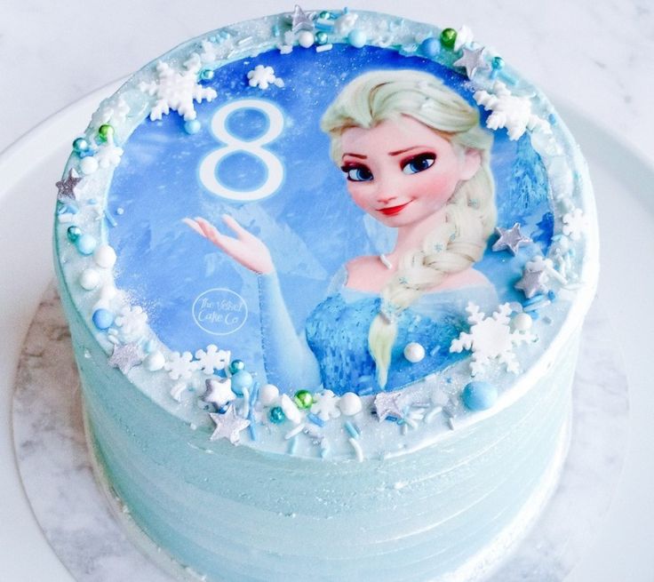 a frozen princess birthday cake on a plate with the number 8 frosted in blue icing